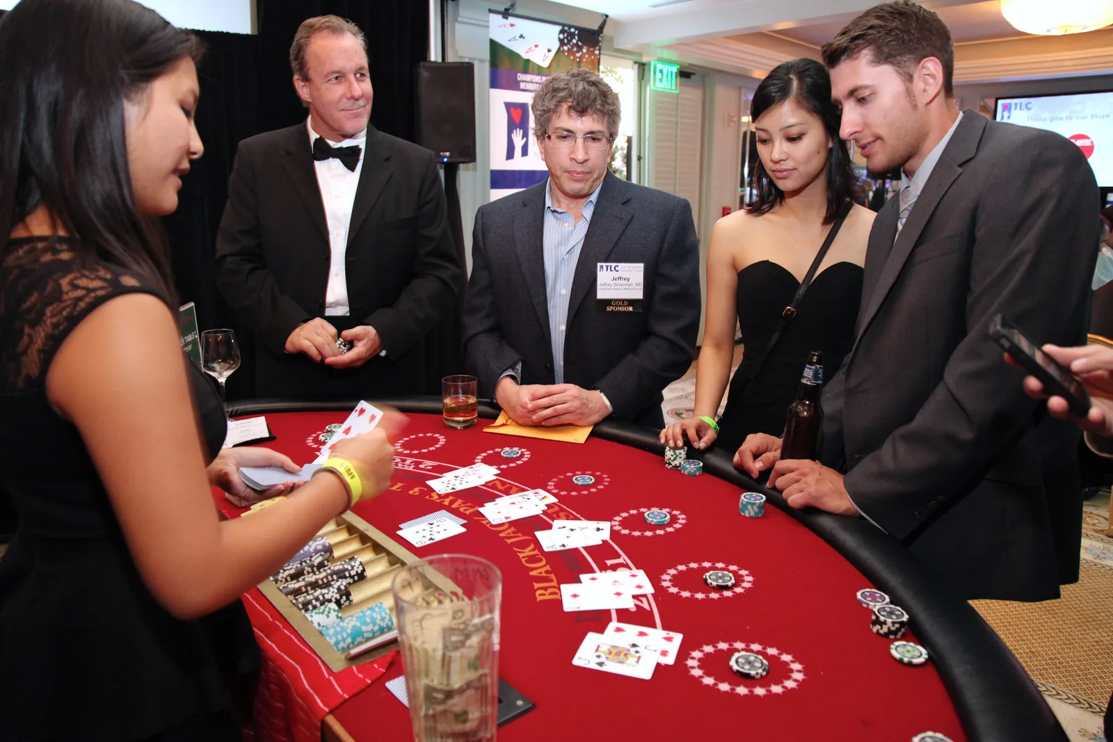 Well-dressed guests at a blackjack table with a professional dealer during a Los Angeles charity casino night